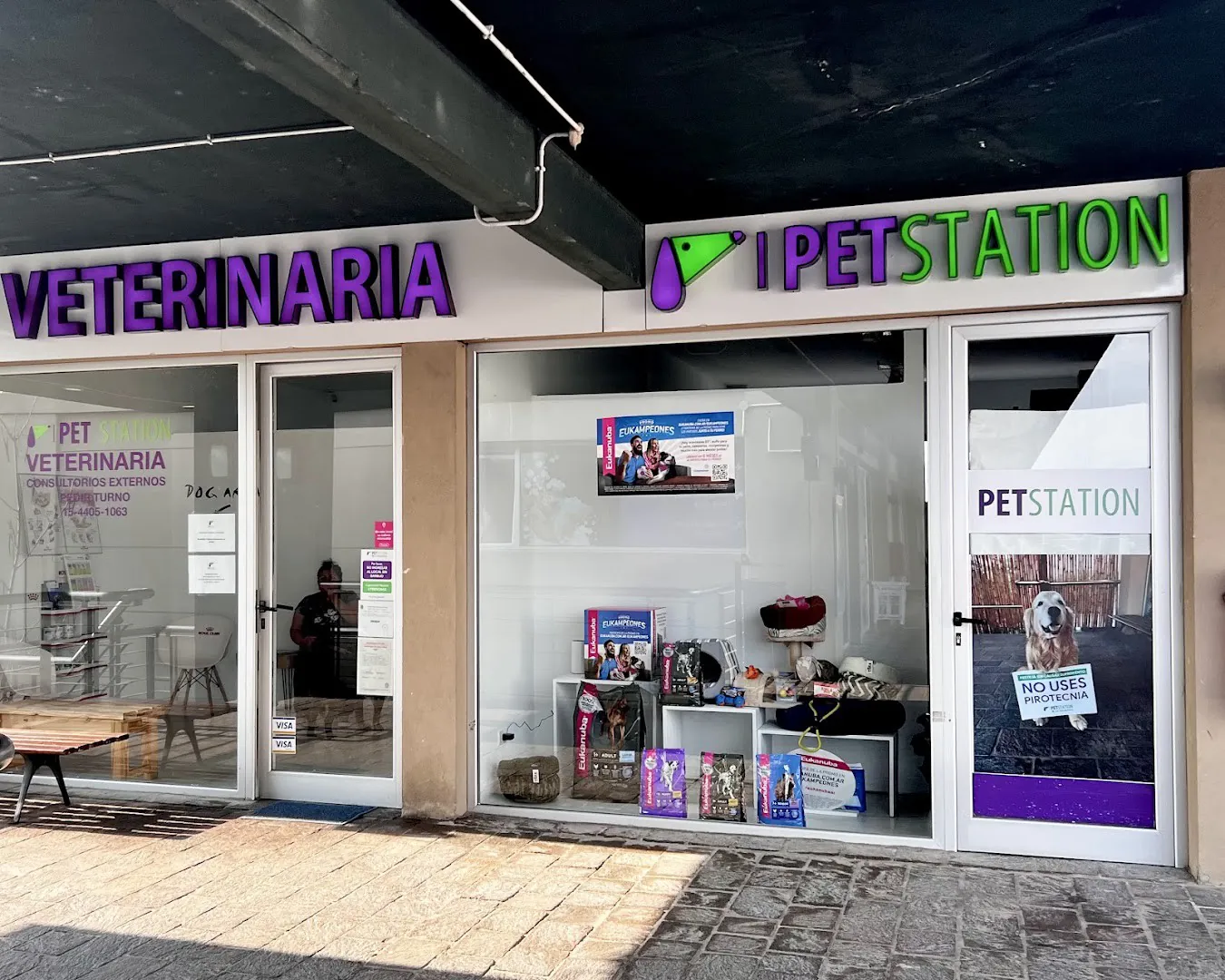 Frente del local con el cartel violeta de Veterinaria y el de Pet Station en verde y violeta